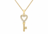 A gold key pendant necklace with a heart-shaped top adorned with small clear stones, shown on a white background.