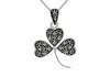 A silver-toned shamrock pendant necklace embellished with small black and champagne-colored stones, shown on a white background.